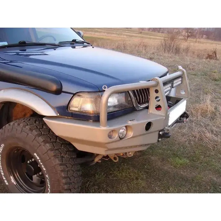 Støtfanger foran Mitsubishi Pajero Sport 96-00 i sølvgrå metall med integrerte lykter, montert på bil.