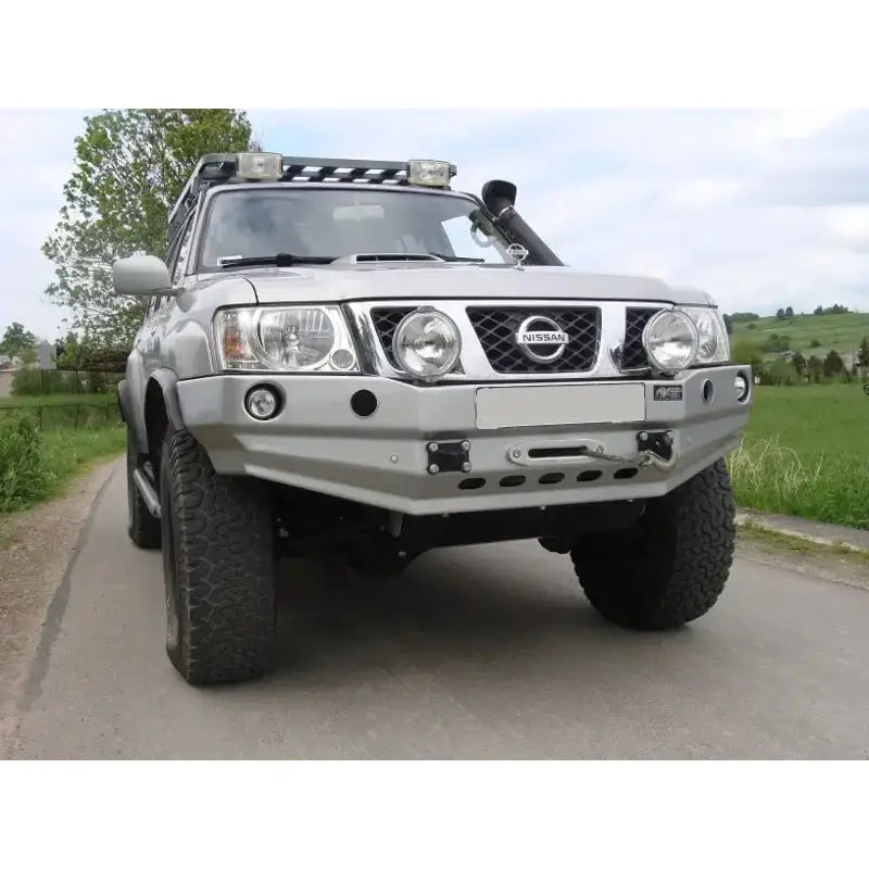 Front bumper på Nissan Patrol Y61 med stor metallstøtfanger, kraftige dekk og ekstra taklys.