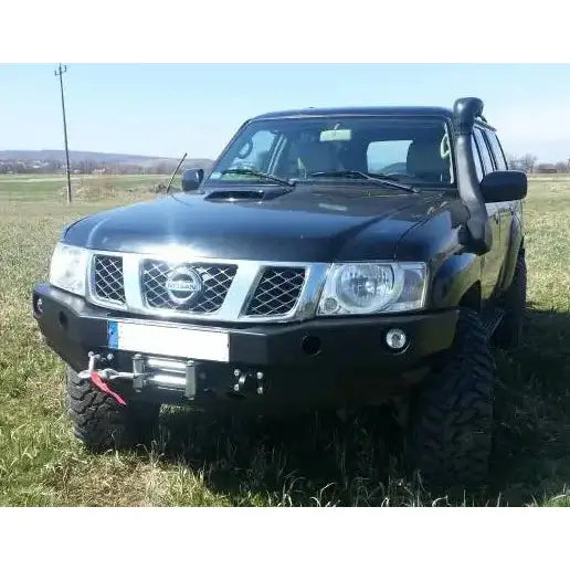 Frontbumper på Nissan Patrol Y61 med metallstøtfanger, vinsj og snorkel, fotografert utendørs på gress.