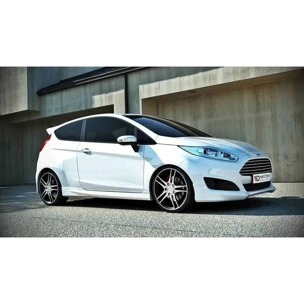 Frontfanger på Ford Fiesta Mk7 Facelift med sorte alufelger og sotede vinduer foran murbygning.