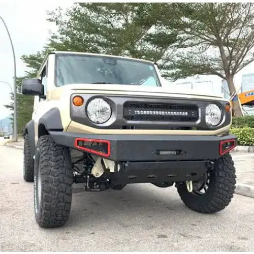 Frontfanger av stål på Suzuki Jimny 18- med LED-lyslist, store terrengdekk og beige karosseri.