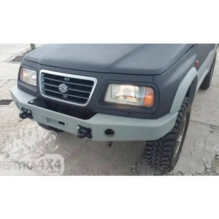 Frontfanger til Suzuki Vitara 2.0 V6 95-97 i lys grått metall med hovedlykter og terrengdekk.