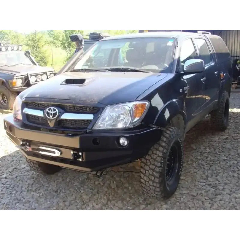 Støtfanger foran på Toyota Hilux 05-11 med kraftig stålfanger og grove terrengdekk, sett skrått forfra.