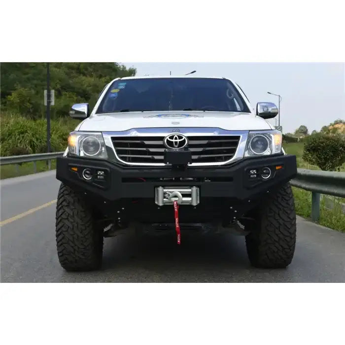 Støtfanger foran til Toyota Hilux 11-15, sort metall med vinsj montert, sett rett forfra utendørs.