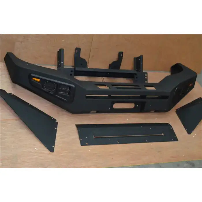 Front bumper til Toyota Hilux 11-15 sett ovenfra med oransje refleks og fire løse plater på trefarget underlag.