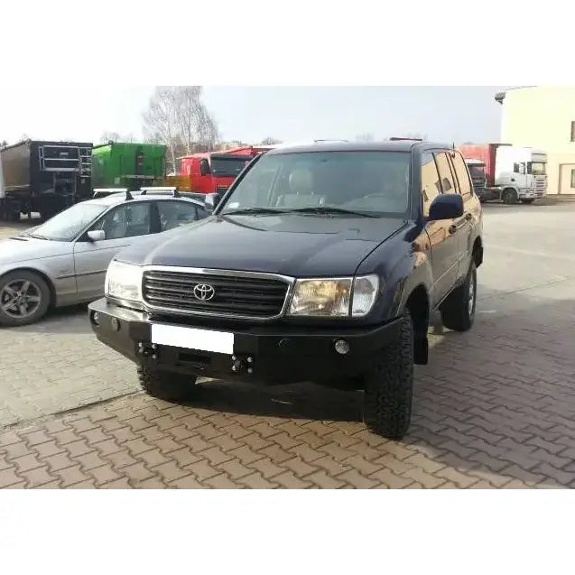 Front bumper på Toyota Land Cruiser J100 med metallfanger og store terrengdekk, parkert utendørs.
