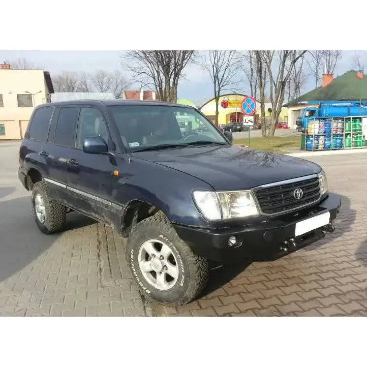 Frontbumper til Toyota Land Cruiser J100 montert på mørkeblå SUV med terrengdekk og sølvfelger.