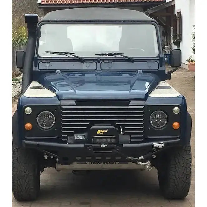 Front bumper på Land Rover Defender med sort støtfanger, vinsj, runde hovedlykter og oransje blinklys.