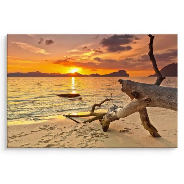 Lerretsbilde av strand ved solnedgang, drivved i forgrunnen og varme gule samt oransje toner i motivet.
