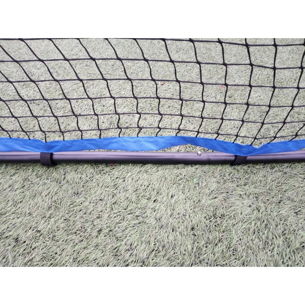 Stuivend Stort Trampoline, detalj av svart sikkerhetsnett og blå kant festet til metallstang på kunstgress.