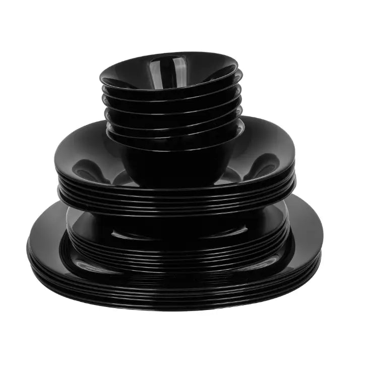 Svart middagsservise med 24 deler, stablede kvadratiske tallerkener og boller sett forfra mot hvit bakgrunn.