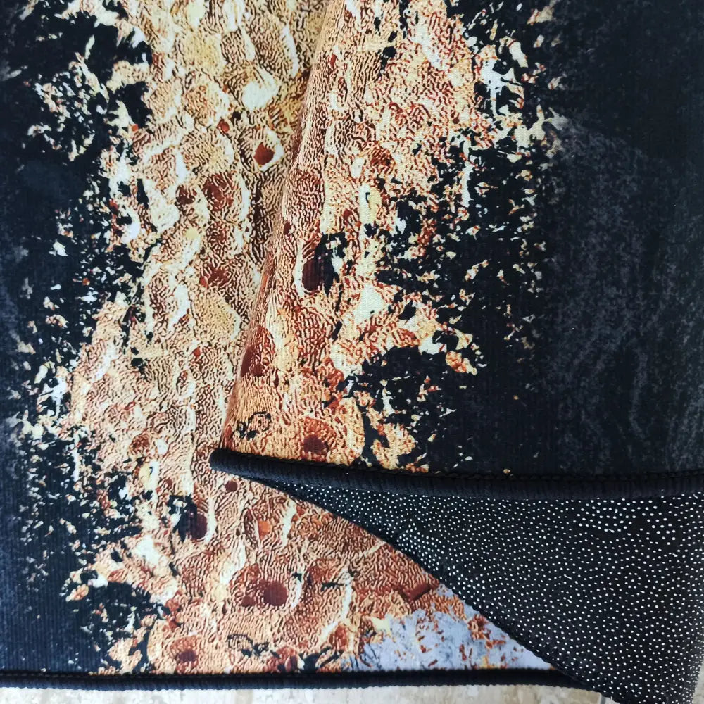 Svart og Gull Tepe, nærbilde av abstrakt mønster og brettet hjørne med gummiert antiskli-underside.