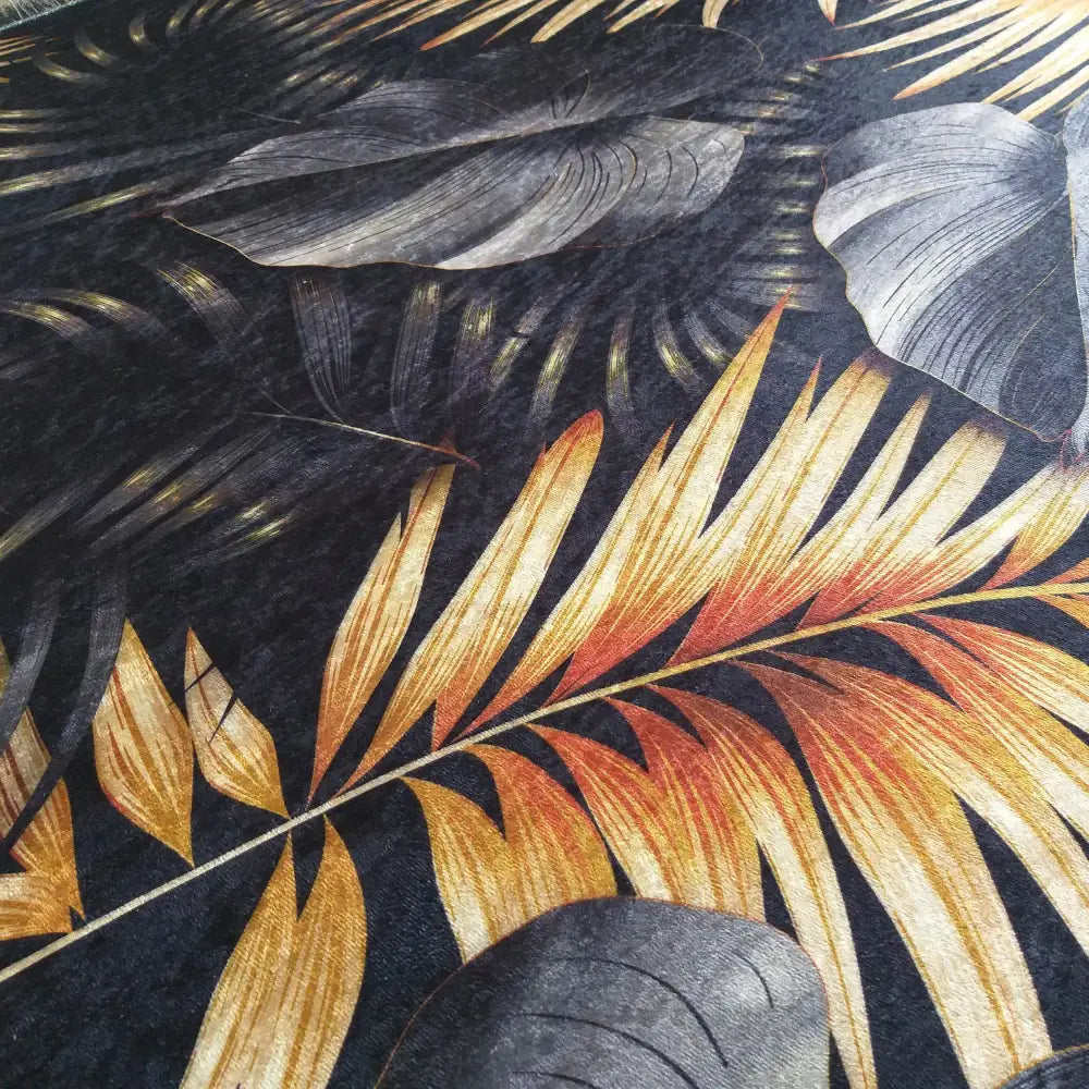 Svart og gull teppe 160 x 220 cm, nærbilde av tropisk bladverk med struktur og fargerike detaljer.