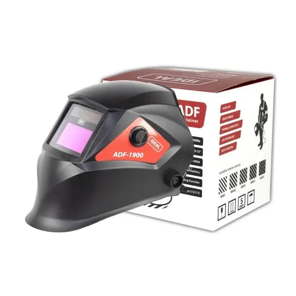 Sort sveisemaske med røde detaljer og synlig justeringsknapp, plassert foran informativ produkteske.