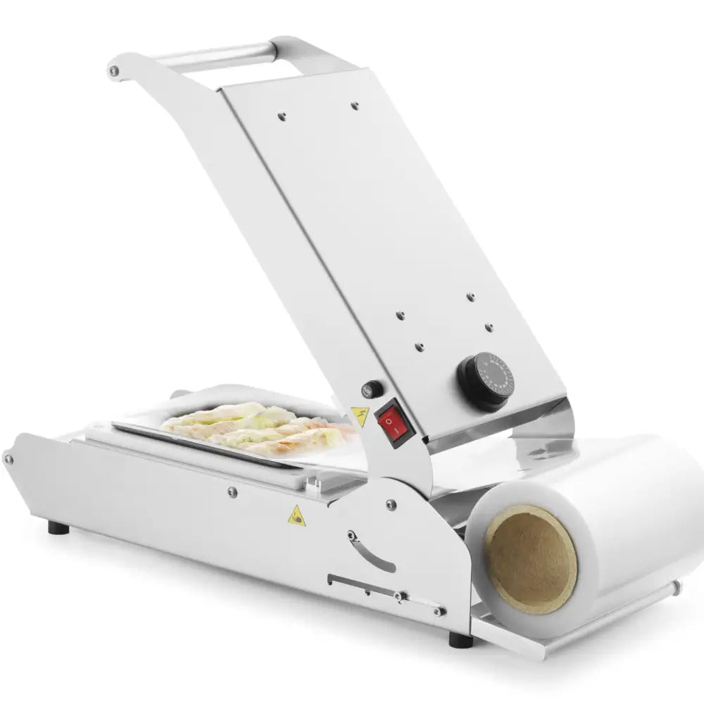 Sveisemaskin for brett og kopper, sidevisning med åpent lokk, plastfilm og fersk mat i maskinen.