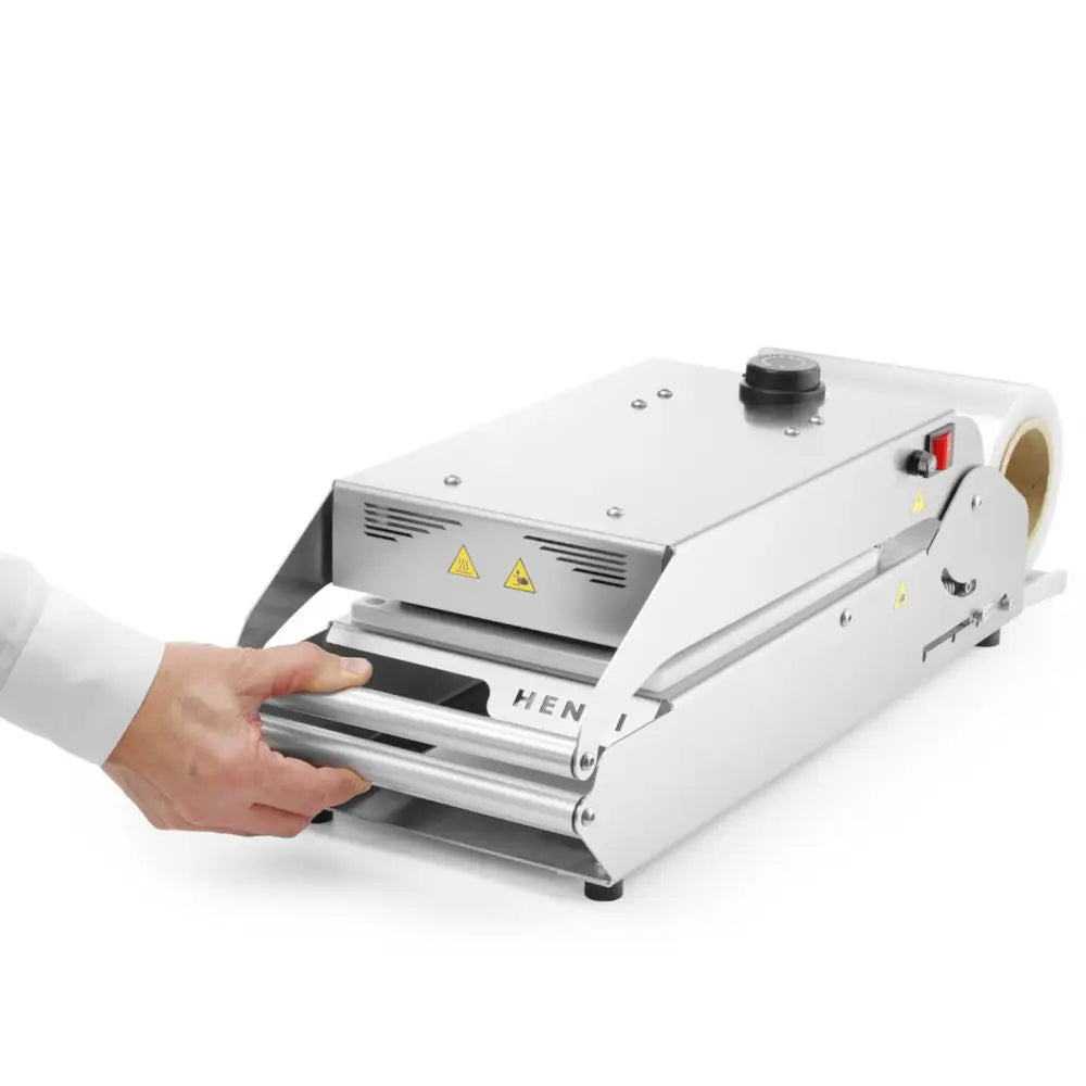 Sveisemaskin for brett og kopper med PE-matrise, skråvisning med hånd som betjener håndtaket og materialrull bak.