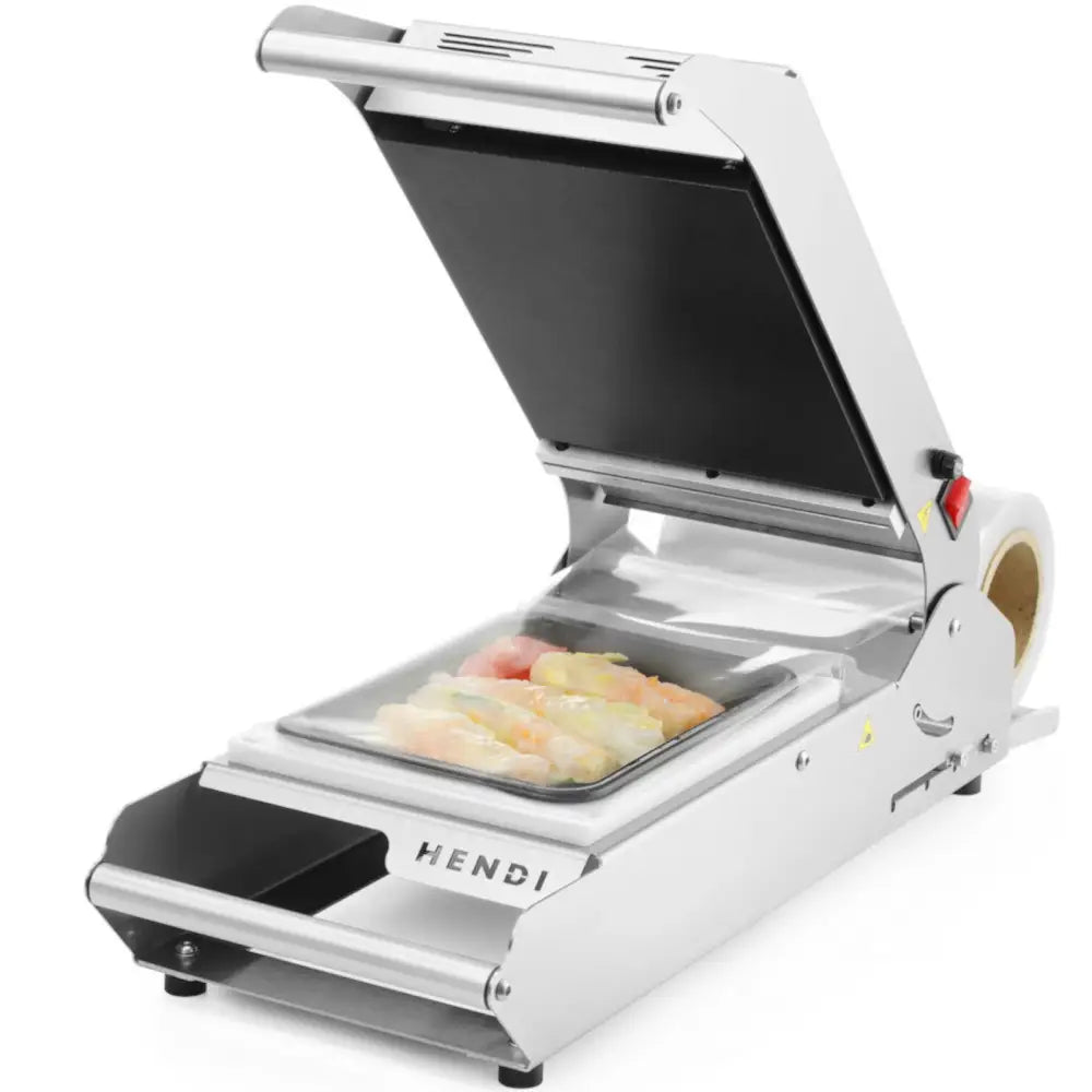 Sveisemaskin for brett og kopper, sett fra skrå vinkel med åpent lokk og plastboks med mat i maskinen.