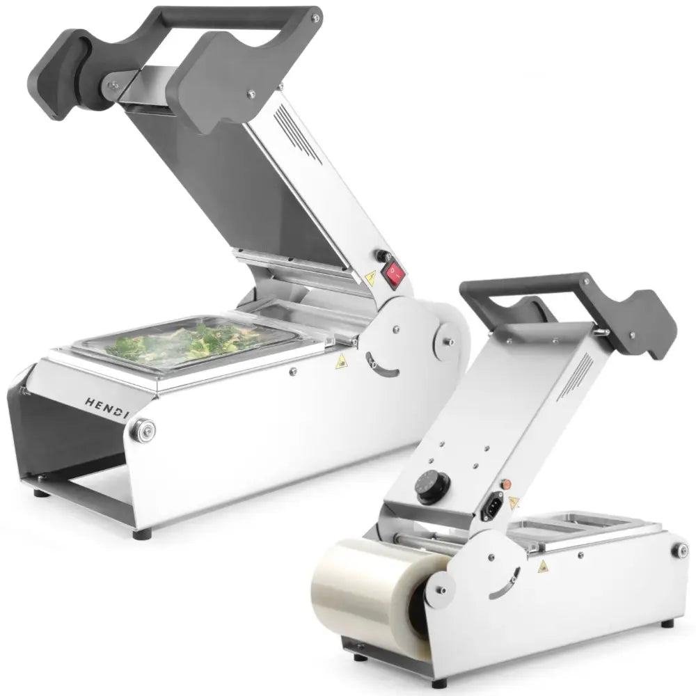 Sveisemaskin for takeaway-matbeholdere, én med åpent lokk som viser plastinnpakket beholder, den andre med filmrull.