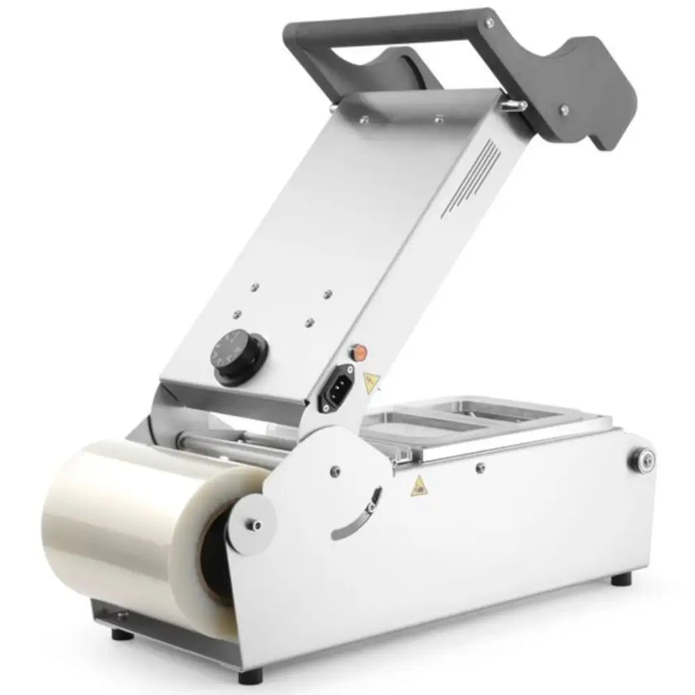 Sveisemaskin for takeaway matbeholdere, skråvisning med plastfilm og justeringshjul synlig på siden.