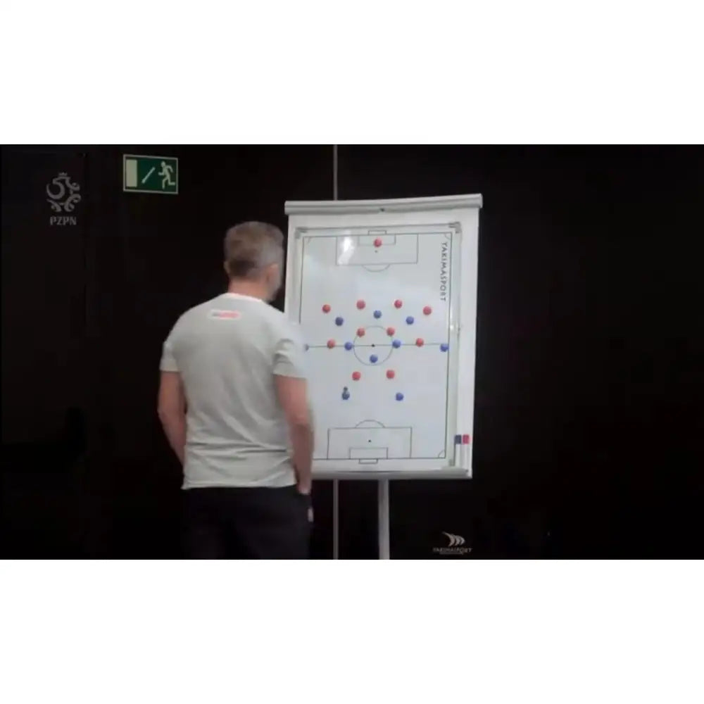 Taktisk fotballtavle 60x90 cm på staffeli, mann demonstrerer formasjoner med røde og blå markører.