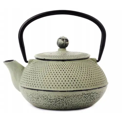 Tekanne for brygging, lys grønn støpejernskanne med prikkemønstret overflate og sort buet håndtak.