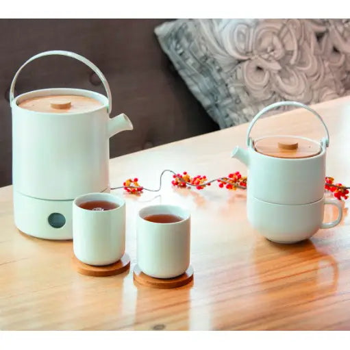 Tekanne Sett Umea, hvit keramikk med trelokk og metallhåndtak, servert med to tekopper på trefat.