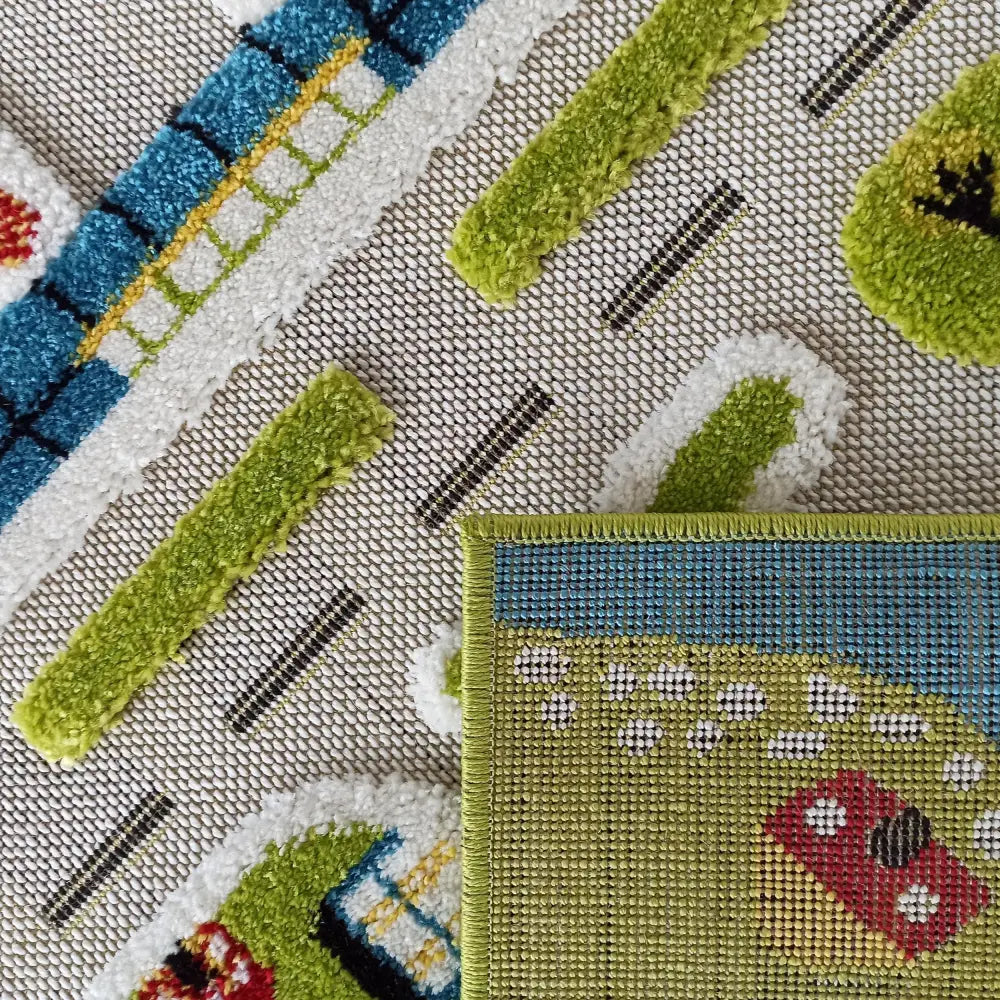 Tepe Barn lekematte, nærbilde av veimotiv i blått og grønt med brettet hjørne som viser undersiden og sømkant.