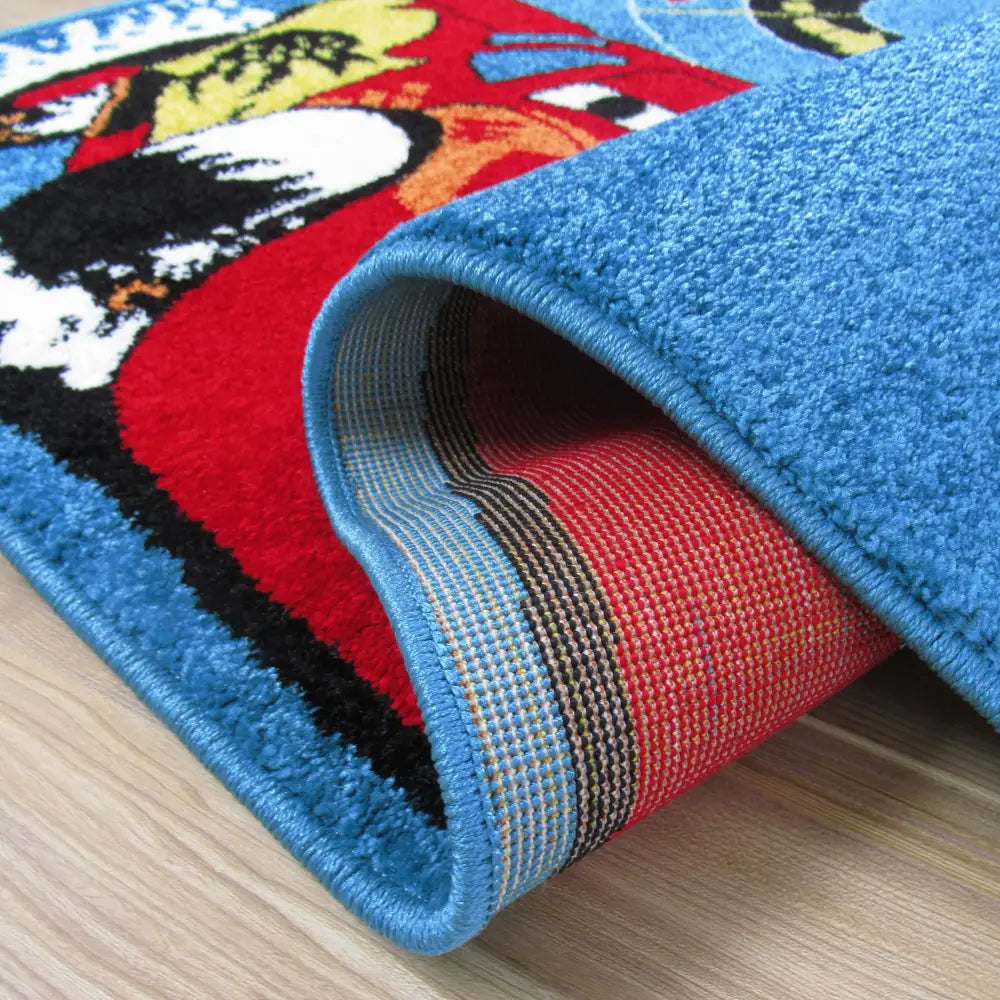 Tepe Bella-teppe i mørkeblått, nærbilde av blå kant og underside mot lyst tregulv, tekstur synlig.