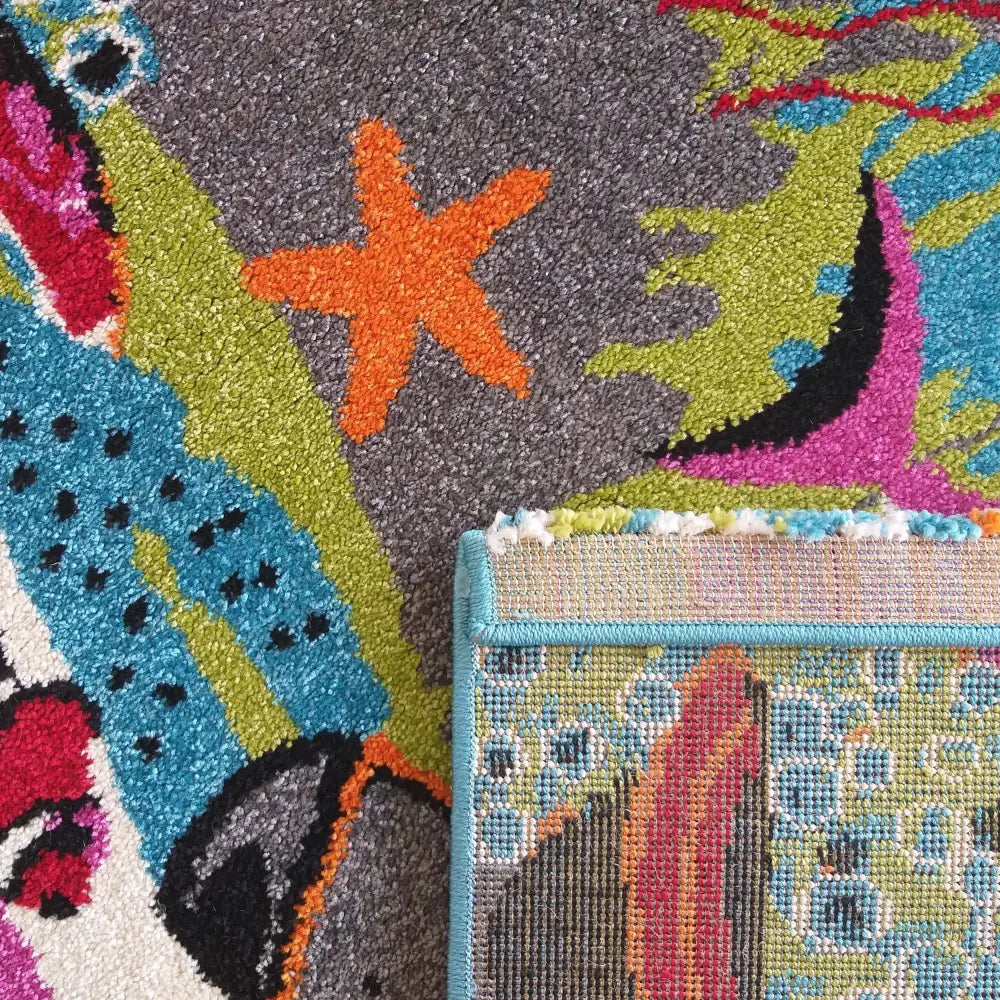 Tepe Bella teppe i blått, nærbilde av abstrakt mønster med oransje sjøstjerne og synlig baksidetekstur.