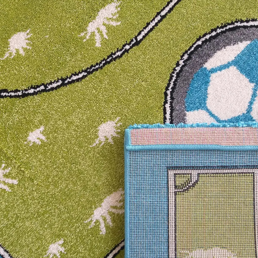 Tepe Bella barneteppe i grønt med fotballdesign, nærbilde av bakside, kant og fotballdetaljer.