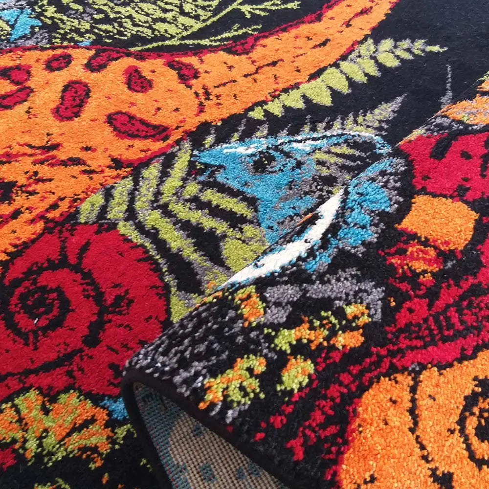 Tepe Bella teppe med flerfarget bladmønster, nærbilde av brettet kant som viser teppets tykkelse.