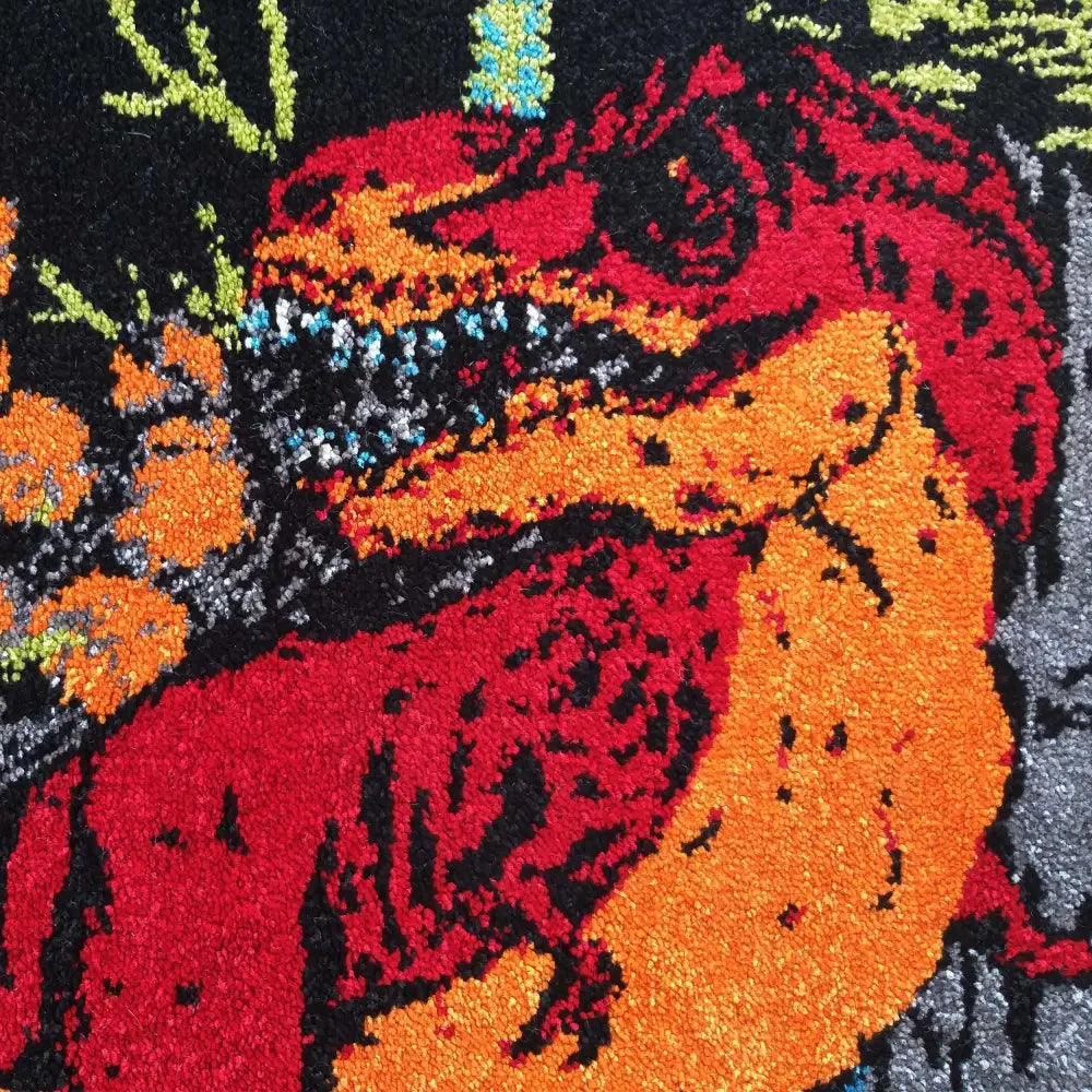 Tepe Bella teppe, nærbilde av rødt, oransje og svart dinosaurmotiv med blomsterdetaljer og grov tekstur.