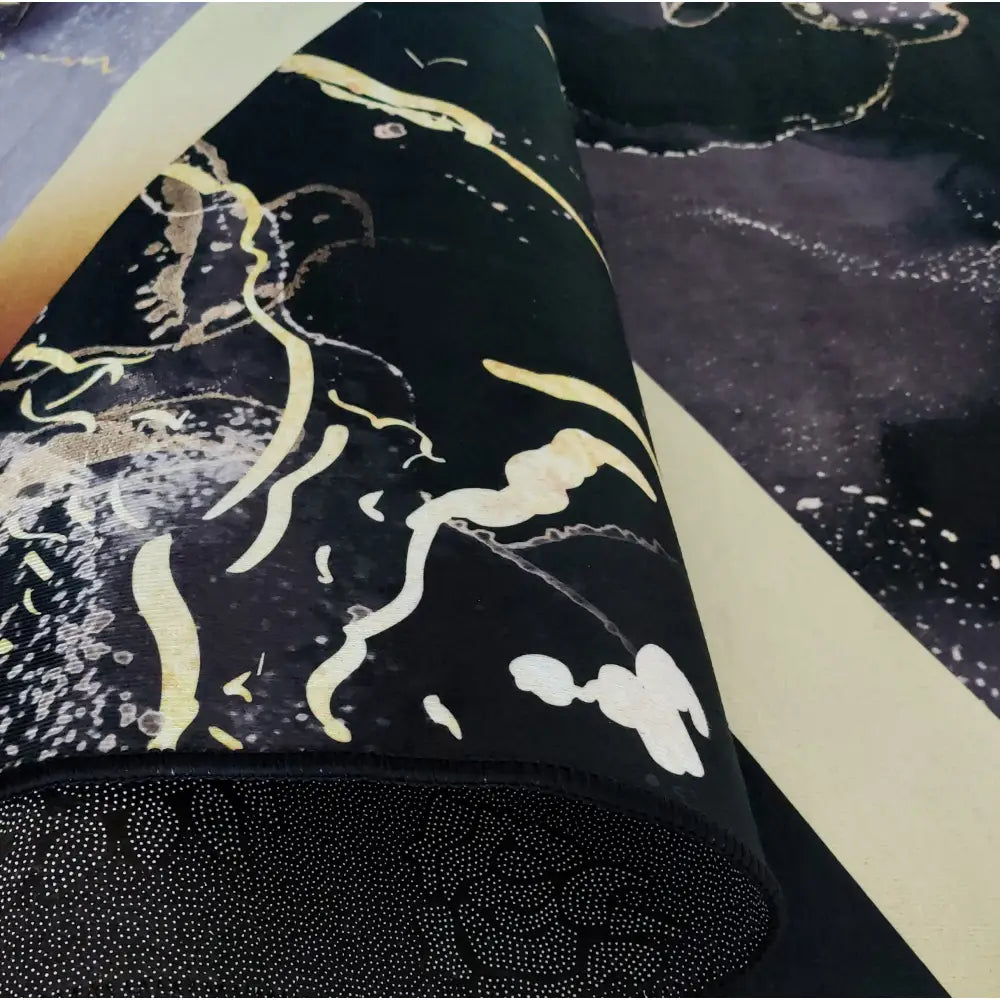 Tepe Black and Gold-matte, nærbilde av sammenrullet svart overflate med gule og hvite abstrakte mønstre.