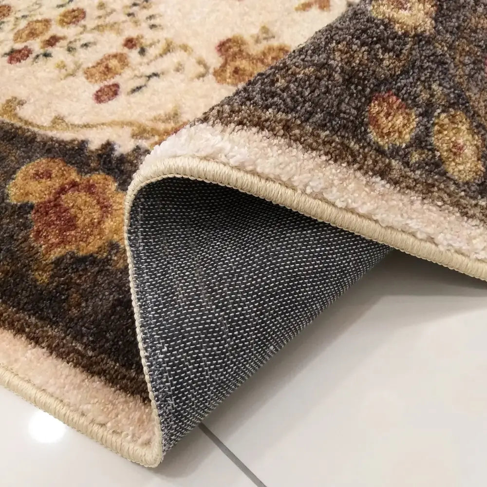 Tepe Casablanca teppe i brun, nærbilde av blomstermønster og oppbrettet hjørne som viser baksiden.