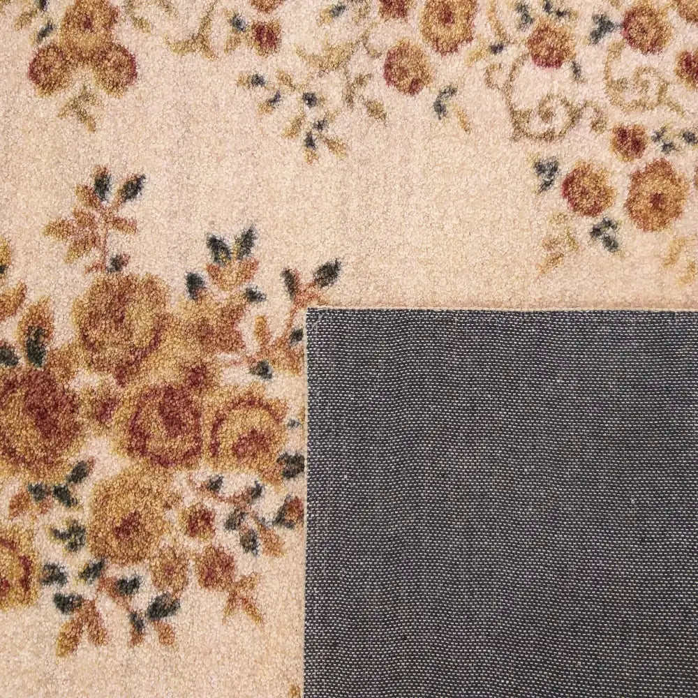 Beige teppe Casablanca med blomstermønster i brunt og grønt, nærbilde av hjørne brettet opp for å vise baksiden.