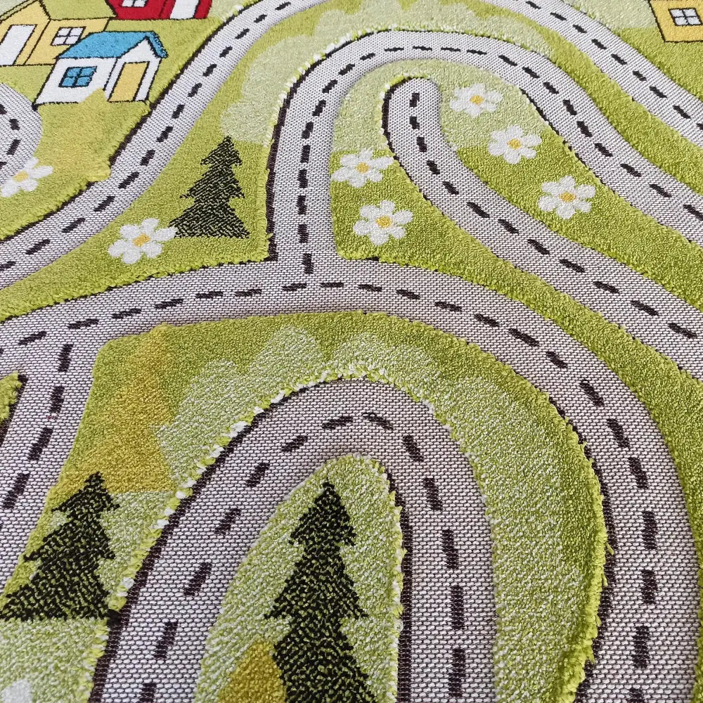 Grønt barneteppe med veimønster, blomster, trær og hus, nærbilde av tekstur og fargerike detaljer.