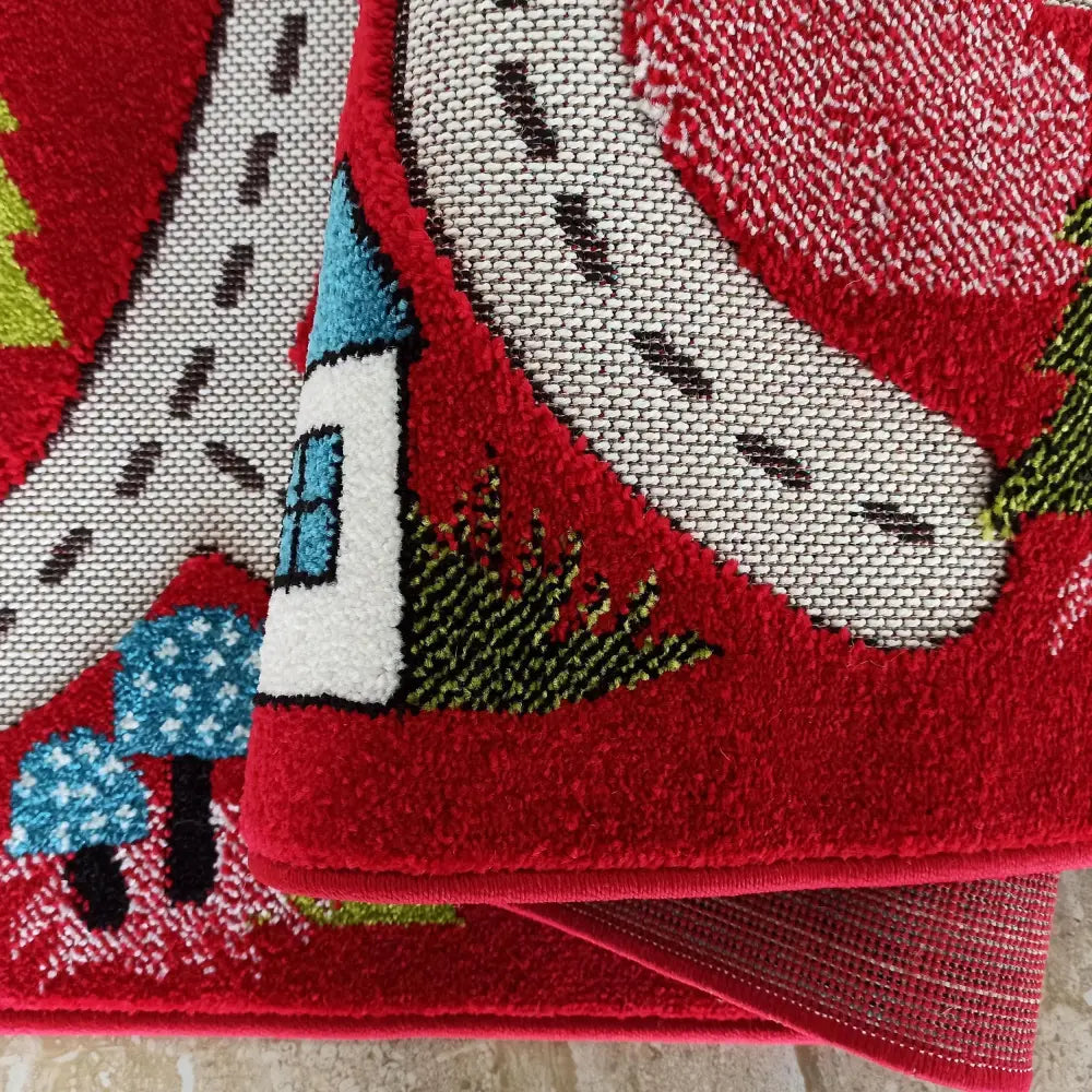 Tepe Color Kids 02 teppe, nærbilde av veimotiv, hus og trær i rødt, blått og grønt, brettet hjørne.