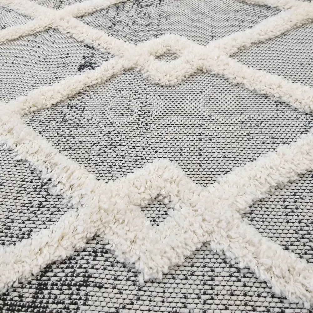 Tepe DELI 02 teppe, nærbilde av hvitt, opphøyd rutemønster på grå bakgrunn med myk tekstur.