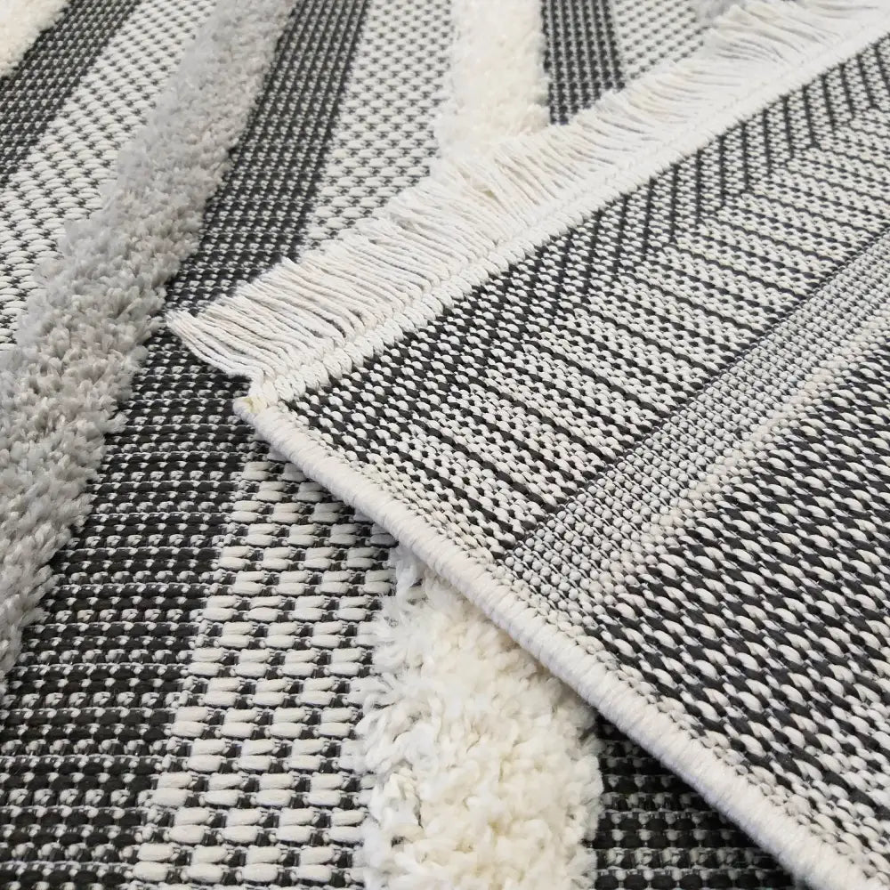 Tepe DELI 03 teppe, nærbilde av grå, svarte og hvite striper med varierende vev og frynset kant.