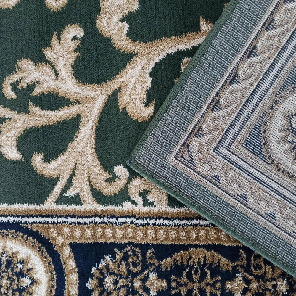 Tepe Eksklusiv teppe i grønt med beige ornamentikk, nærbilde av hjørnekant og synlig bakside.