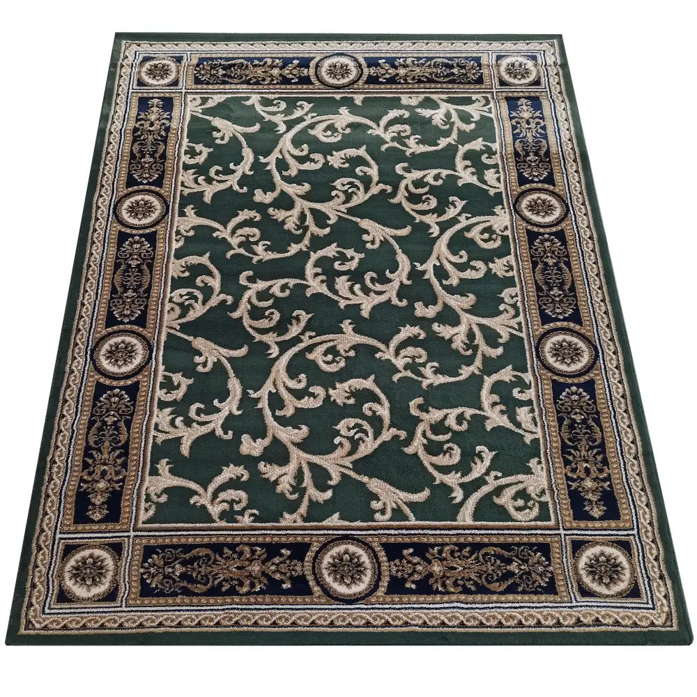 Grønt rektangulært teppe med lyse klassiske mønstre, bred mørk kant og detaljerte ornamenter, sett ovenfra.