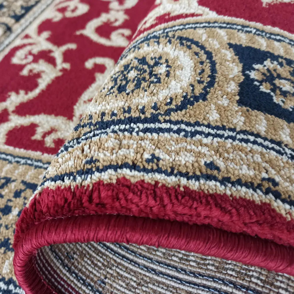 Tepe Eksklusiv teppe, rød 80 x 150 cm, nærbilde av rullet kant med markert tekstur og fargerikt mønster.