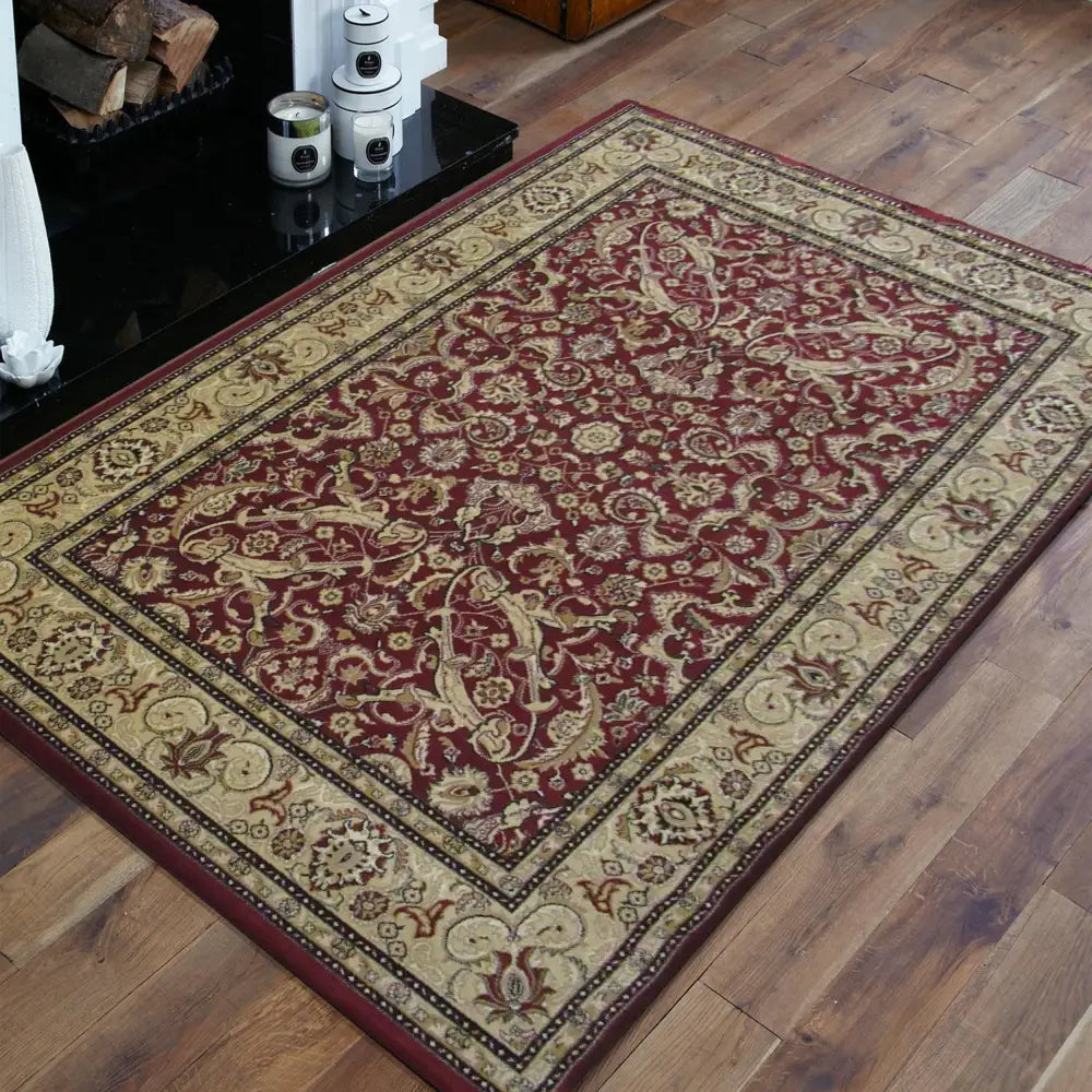 Tepe Eksklusiv 02 teppe, burgunderrød med kremkant og klassisk blomstermønster, skrått vist på tregulv.