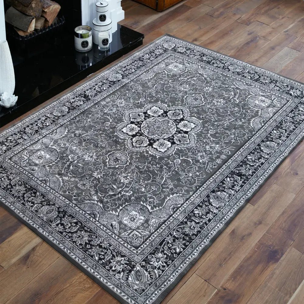 Tepe Eksklusiv 03 grått teppe 160 x 220 cm, sett ovenfra på mørkt tregulv ved peis, orientalsk mønster.