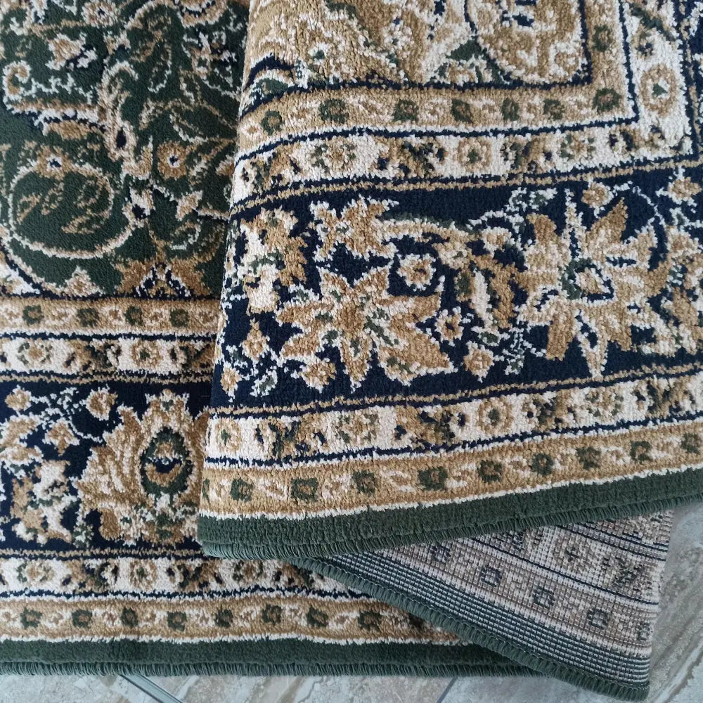 Tepe Eksklusiv teppe i grønn, nærbilde av kantdetaljer og baksidens rutete vevstruktur.