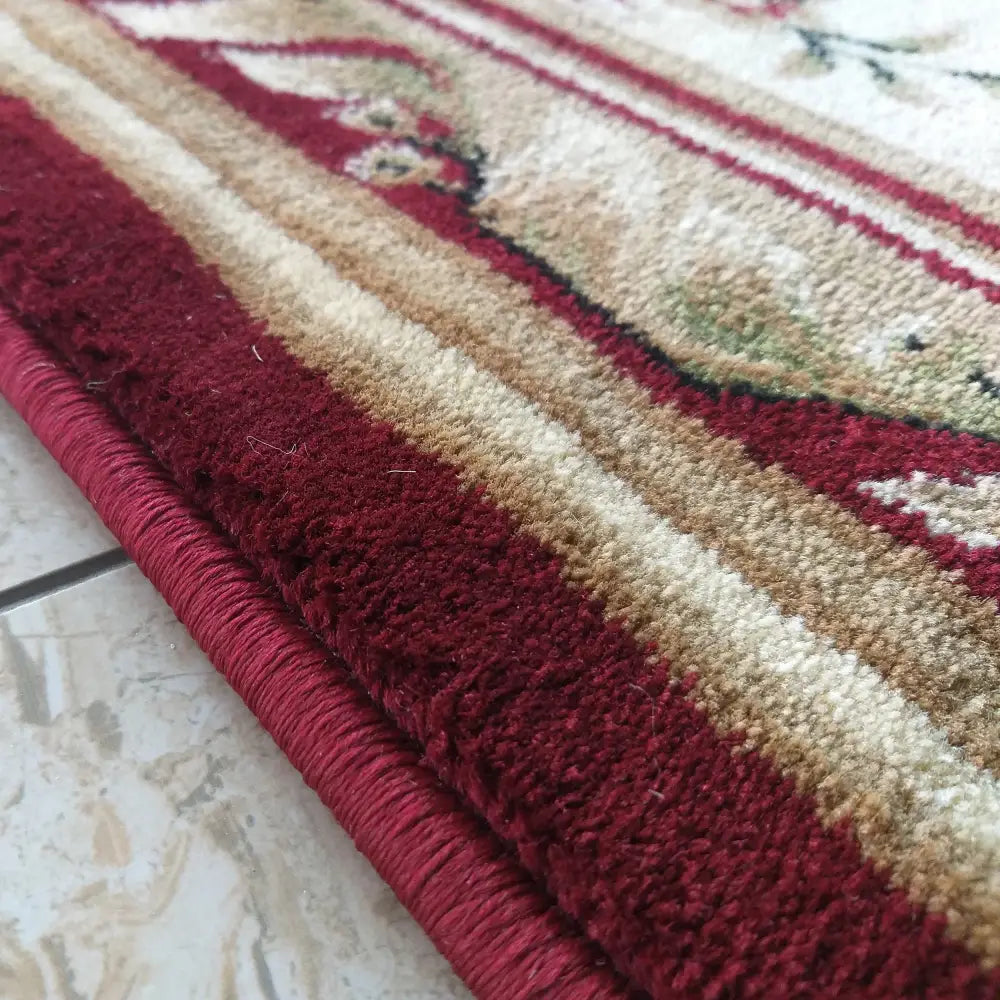 Tepe Eksklusiv 04 teppe, nærbilde av burgunder rosett-mønster, viser kantens tykkelse og fibrenes struktur.