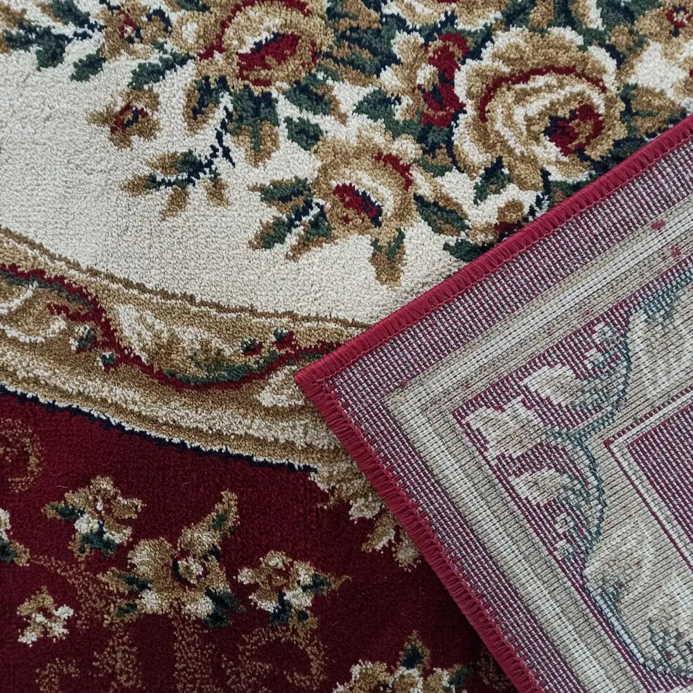 Tepe Eksklusiv 04 N teppe, nærbilde av blomstermønster, teksturert veving og rød kant i hjørnet.