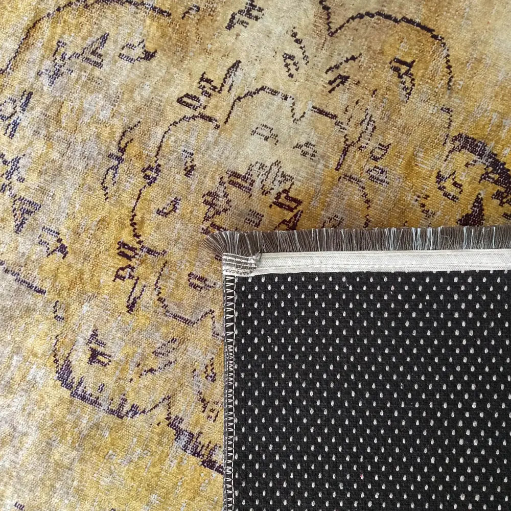 Tepe Eksklusiv Gulltæppe, nærbilde av oppbrettet hjørne, viser sort antisklibakside, frynser og fargerikt mønster.