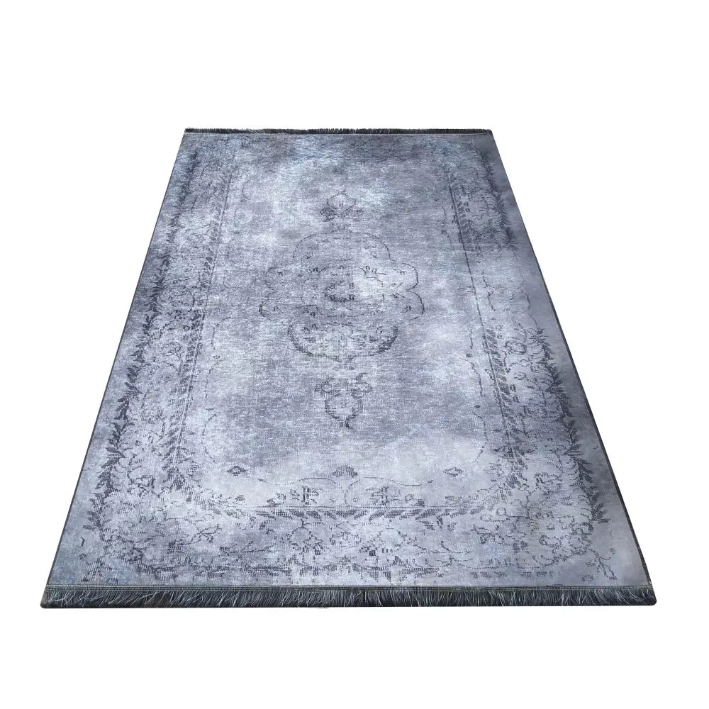 Tepe Elegant teppe i gråtoner, klassisk ornamentmønster, sett ovenfra med synlige frynser på kortsiden.