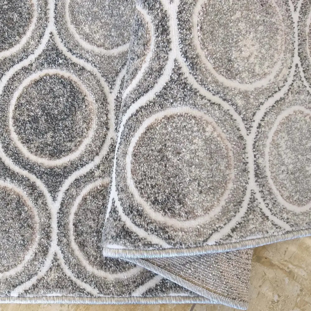 Tepe Enigma teppe grå 160 x 220 cm, nærbilde av brettet hjørne med sirkelmønster og tydelig tekstur.